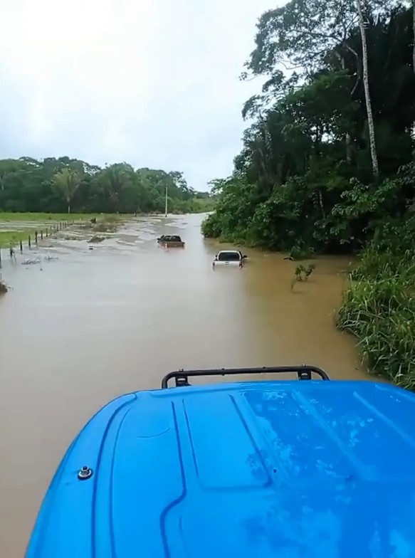 Caminhonetes ficam quase encobertas em rodovia após rio transbordar em